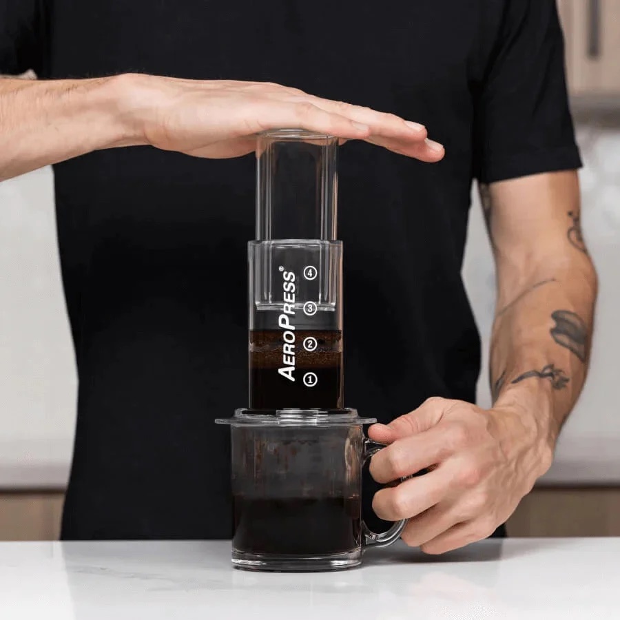 Overhead view of hands assembling an AeroPress on a kitchen counter